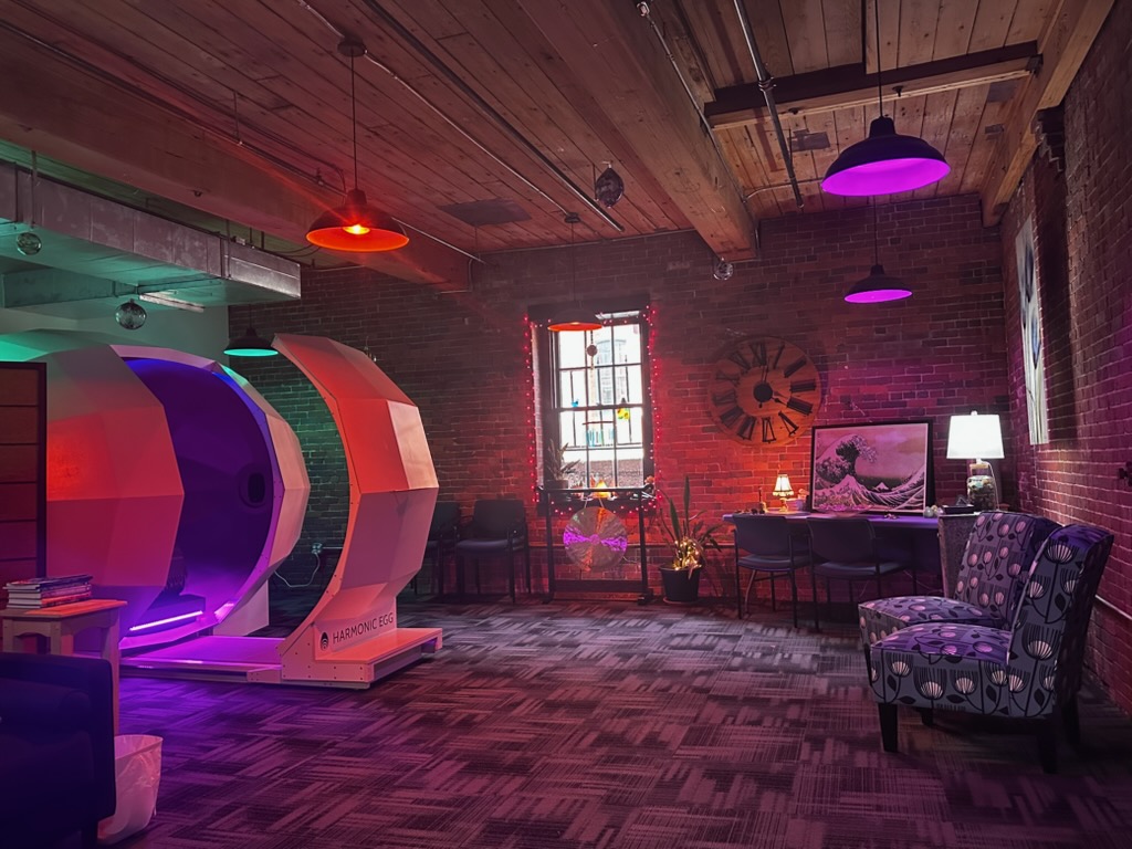 Wide view of the Healing Waves studio with the Harmonic Egg, brick walls, and lounge seating