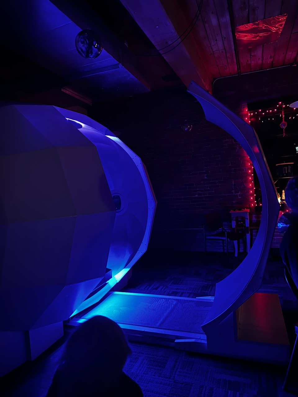 The Harmonic Egg lit from within by deep blue light in a dim studio